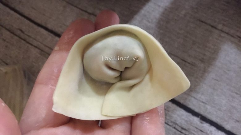 葱油拌馄饨,接着对折,再把下方两角相叠粘住,成元宝状