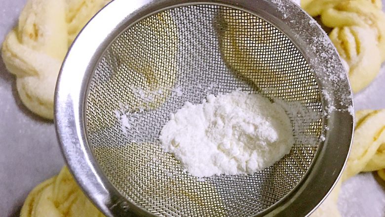 孜然芝麻花环面包,二次发酵完成后,预热烤箱180度
用一个小漏勺舀取一点面粉,筛在每个小花环面包上
表面也可以刷蛋液,在揉面团时预留一点蛋液即可
