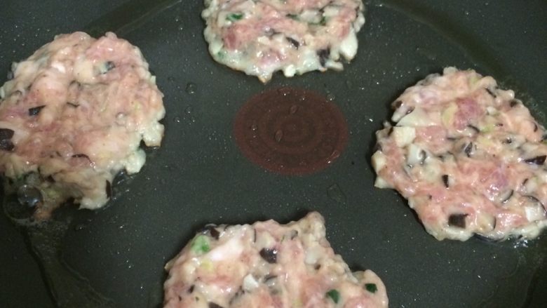 香煎香菇肉饼,平底锅倒入少许油,舀一勺肉馅放入锅中,摊平小火慢煎
