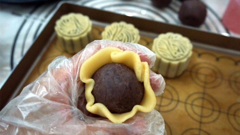 50克广式红豆蓉月饼,面皮压薄后,将馅料包裹好。