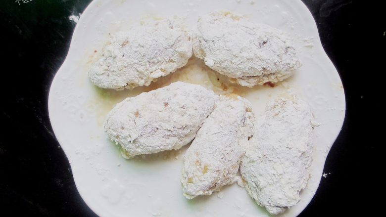 香辣干炸鸡翅,直到鸡翅表面像鳞片一样粘满面粉,待全部鸡翅都裹好后,开始炸制。