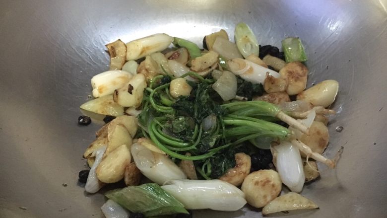 红烧鸡块,煸炒约4~5分钟后蒜发浅金黄色时改中火再放入葱和香菜、8粒冰糖一起煸炒,煸炒至葱有焦糊色,冰糖软化,如图所示。