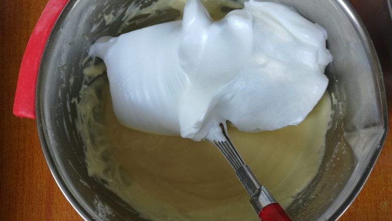 轻乳酪蛋糕,取三分之一蛋白加入到蛋黄糊中,“一”字形搅拌均匀。