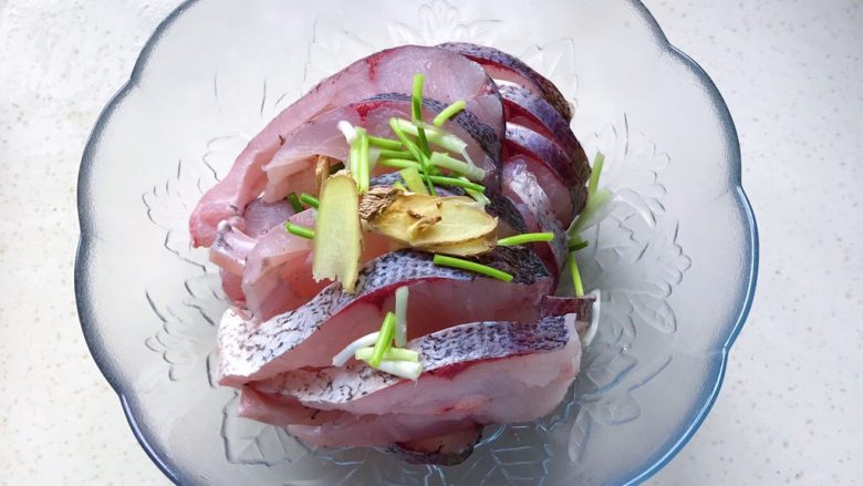 秘制酥鱼,把鱼肉放进容器里,撒上葱白和姜片