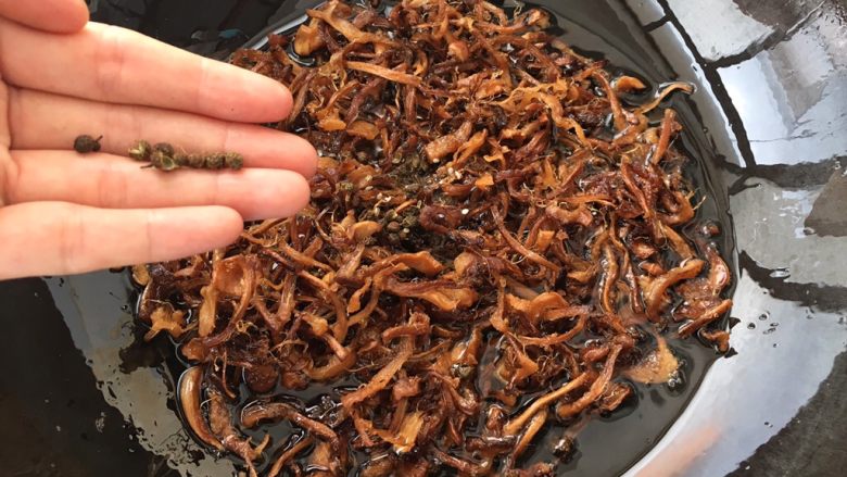 麻辣香菇丝,香菇丝金黄色这个时候就可以关火了,放入花椒粒。