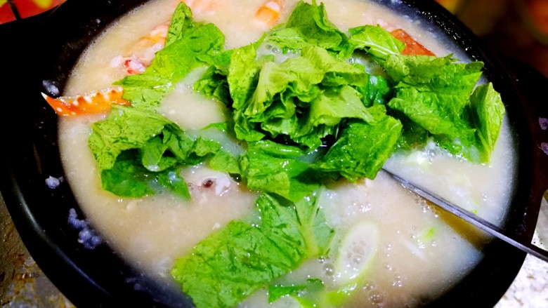 家庭简易版螃蟹海鲜粥,粥煮沸,大约五分钟,海鲜也已经全熟了,倒数滴味极鲜,放入葱花,姜末,小青菜,三十秒关火。