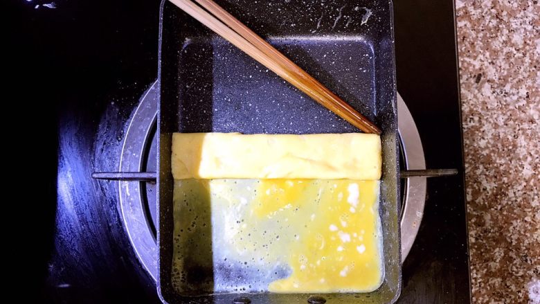 日式厚蛋烧,待蛋液底层成型,但表面还未完全熟的时候用筷子小心的从上往下开始内卷。里层未完全熟的蛋液能把蛋饼牢牢粘住,不会松散,后面的操作会把蛋液全部煎熟的,不用担心