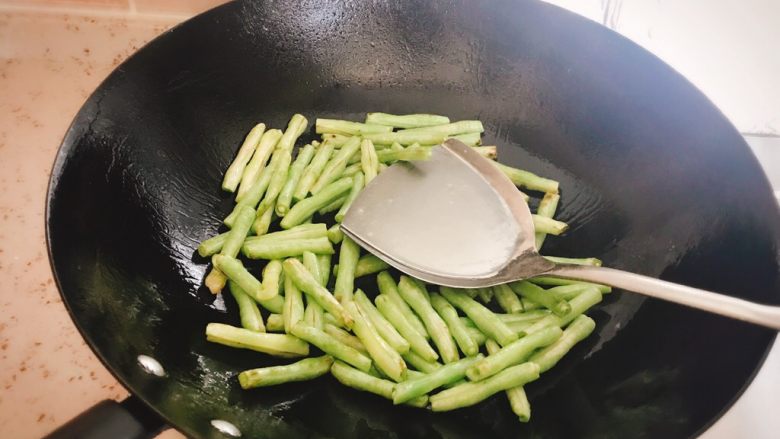 素干煸豆角,用锅铲用力按压,翻炒,使豆角表面起虎皮