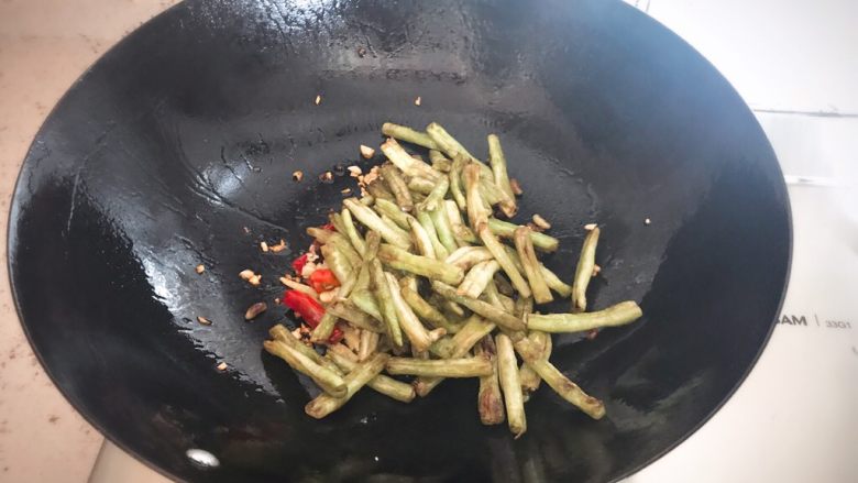 素干煸豆角,配料炒香后,倒入备用的豆角,翻炒,快速给盐,生抽,适量糖