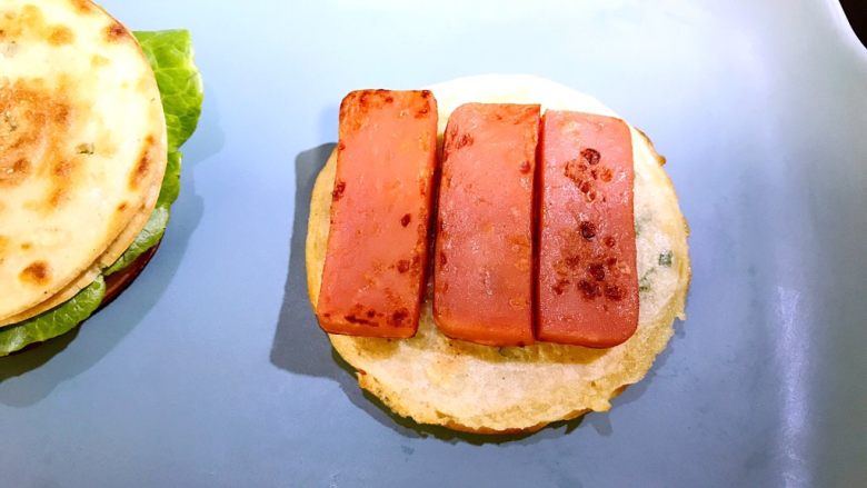 煎饼芝士汉堡,等芝士片充分溶解后,先将铺上鸡肉肠的两层煎饼拿出
