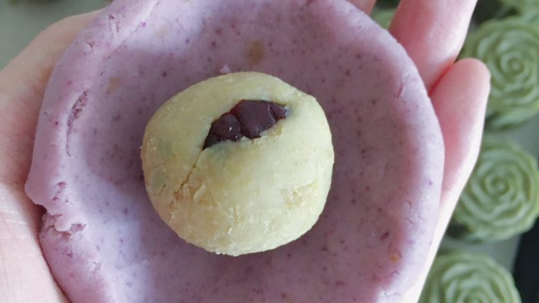 桃山皮板栗月饼,
把紫薯月饼面团放在手掌压扁成片蔓越莓栗子泥放在中间 用虎口的位置推动慢慢转动手使饼皮慢慢包裹
