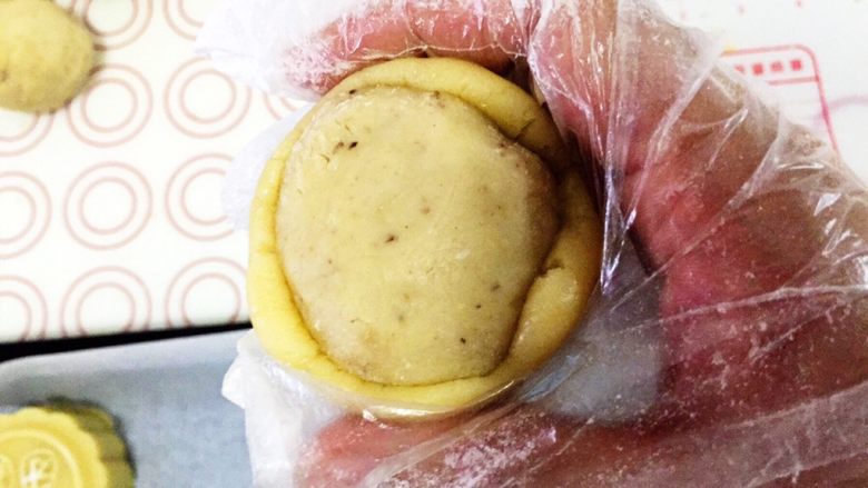 传统广式莲蓉月饼,翻过来,放在右手虎口位置,左手轻轻的托着饼胚底部,右手拇指和食指轻轻地均匀的往上推饼皮