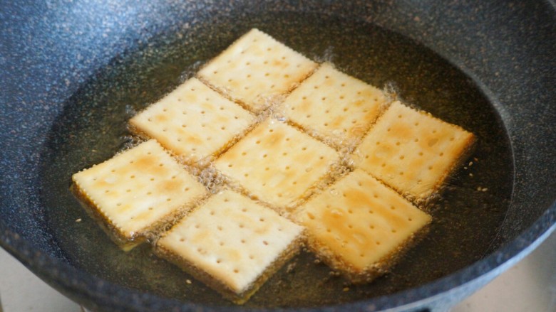 南瓜夹心苏打饼,沿着锅边缓缓放入夹心饼干，全程保持小火慢炸，注意翻面。炸到饼干浮起，表面金黄，沥油出锅。