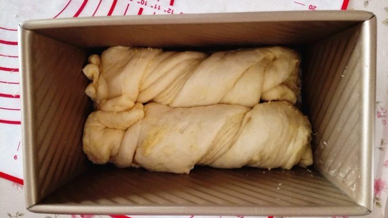 奶黄馅吐司,取一条,扭一下,放入吐司盒里,另一条也如此操作,