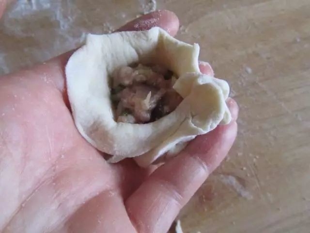 水煎包,把包子皮放在手指上,手指弯曲形成一个窝能放馅,口捏紧就行,包子外型好不好看,不影响吃。