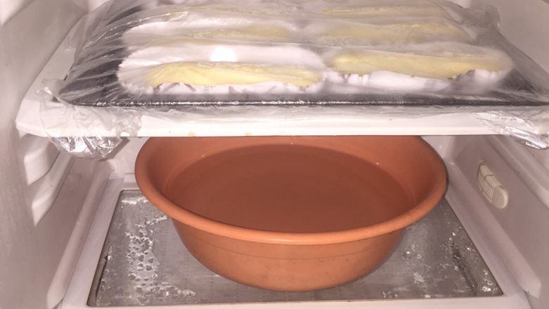香葱芝士面包,开始二发,我用废弃的冰箱做成的简易发酵箱,没有可以借助烤箱,提前放热水让热气充满空间,盖上保鲜膜开始二发,我今天发了40分钟,二发的状态按表面有个指印窝,立马回弹说明可以继续发下,周边塌陷说明发酵过了