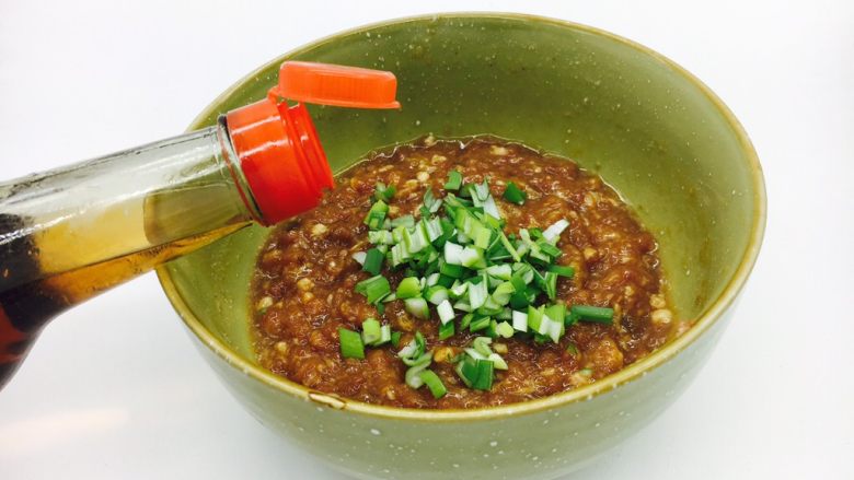 #咸味#  地方特色海鲜汤小云吞 ,放入葱花，在葱花上倒入约1小勺左右的<a style='color:red;display:inline-block;' href='/shicai/ 847'>香油</a>，用<a style='color:red;display:inline-block;' href='/shicai/ 847'>香油</a>把葱花搅拌一下，裹住葱花，再把葱花搅拌至肉馅中去。