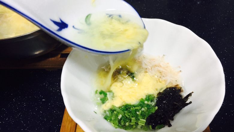 #咸味# 地方特色海鲜汤小云吞 ,往步骤图8的汤碗里倒入小云吞汤,用汤勺搅动一下碗里的汤,香菜、紫菜、小虾皮被滚汤烫熟,最后盛入小云吞即可。