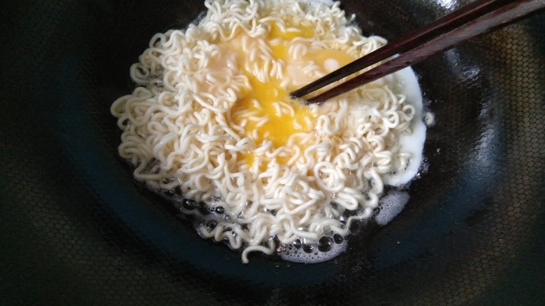 #咸味#泡面卧俩蛋(泡面另类吃法),用筷子,轻轻戳破鸡蛋,使它包裹着泡面。