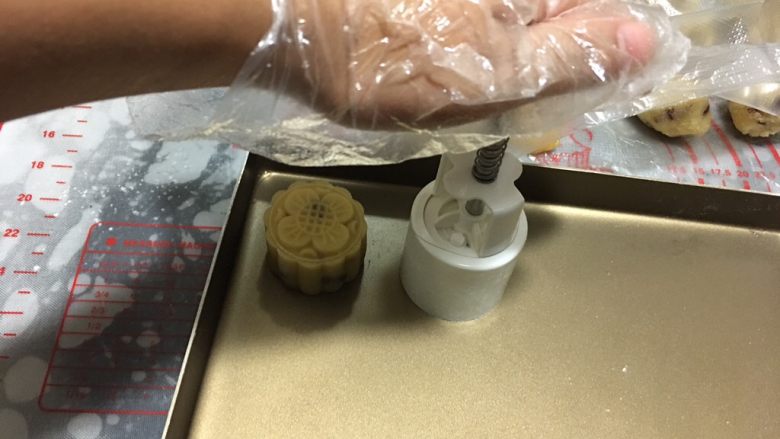 蔓越莓椰蓉月饼,一手压着磨具的上方一手扶着磨具的下面,在轻轻的按压下去,停留3秒,取出磨具即可