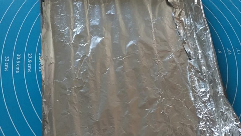 五香烤鸡翅,烤盘上放好锡纸按压整齐!这个是为了到时候油汁不会粘到烤盘上,要不然很难清洗
