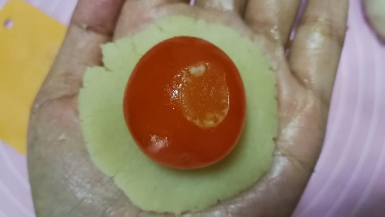 广式莲蓉蛋黄月饼,松弛饼皮的时间可以做馅料,取25g<a style='color:red;display:inline-block;' href='/shicai/ 5405'>莲蓉馅</a>压扁放上一颗<a style='color:red;display:inline-block;' href='/shicai/ 9596'>咸蛋黄</a>(尽量选用小一点的<a style='color:red;display:inline-block;' href='/shicai/ 9596'>咸蛋黄</a>,每个10g左右,太大的可以切半使用,莲蓉包蛋黄总重控制为35g/个),左手掌心托住底部,右手虎口慢慢往上收口,然后团成圆形