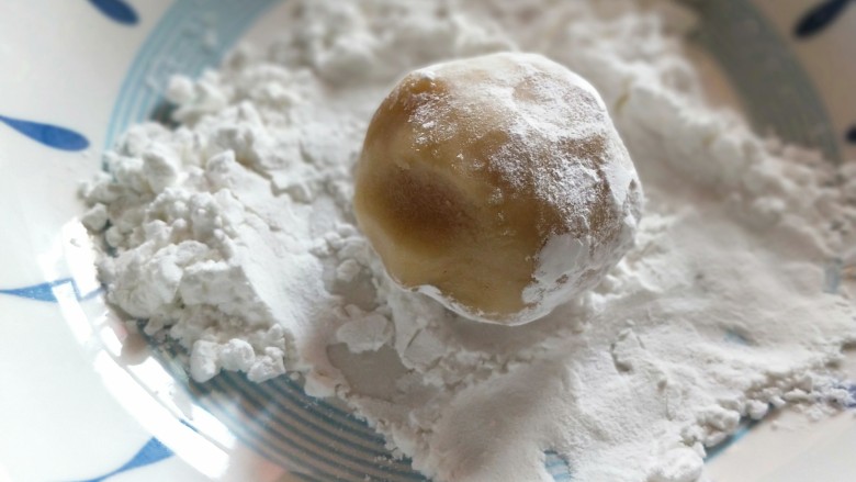 莲蓉蛋黄月饼,将包好的月饼团在盛淀粉的盘子里过一下,拍掉多余淀粉。