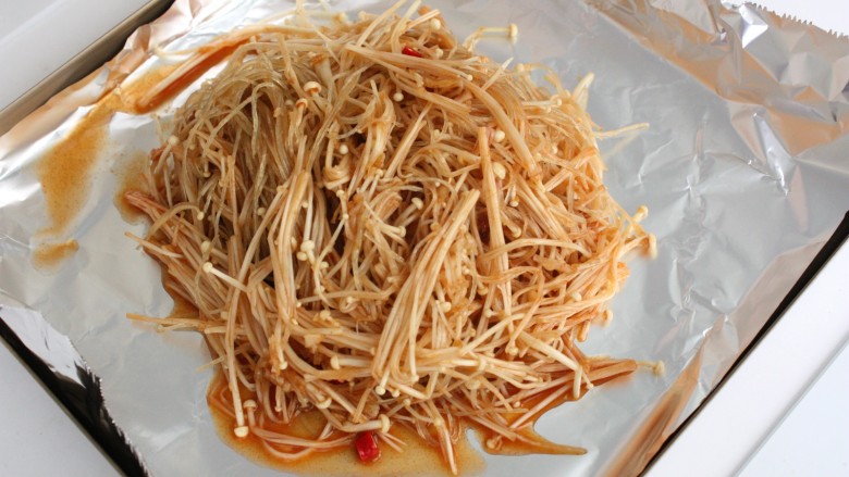 蒜茸烤金针菇,烤盘上铺锡纸,哑光面朝上,把翻拌好的金针菇和粉丝倒在锡纸上。