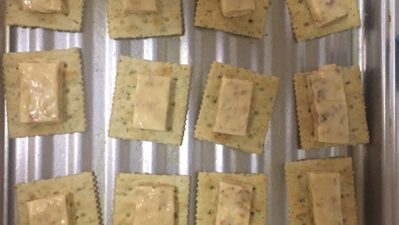 拉丝牛扎糖饼干,取一烤盘,将苏打饼干整齐平铺上面再放一颗牛扎糖,烤箱预热150度烤3分钟至牛扎糖软,取出再依次盖上苏打饼干。