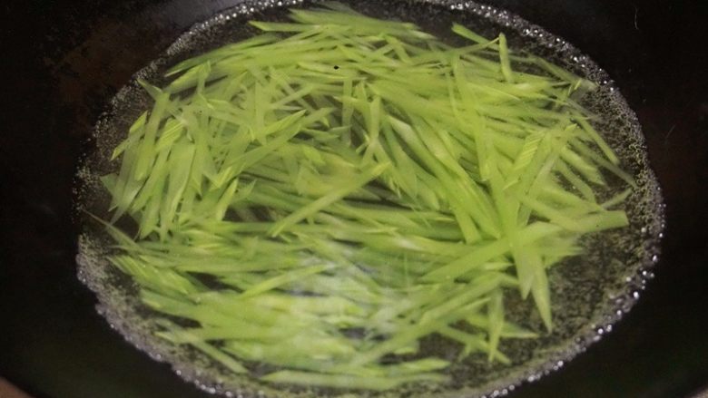 酸椒煮虾球,8.锅内倒入清水下入切好的莴笋丝焯熟捞出放入碗中垫底