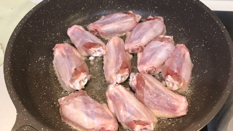 红烧鸡翅鹌鹑蛋,烧热锅子(不沾的)。把处理好的鸡翅一个一个放进去。(记得皮向下先煎)。皮变色后翻面煎一下再翻面。把鸡皮的油煎出来。(一会爆香的时候用)