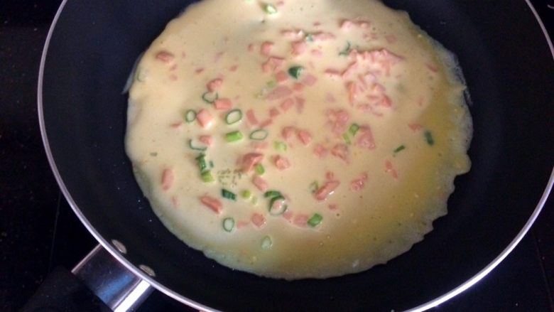 火腿葱花饼,盛2勺面糊倒入锅,轻轻晃动锅,将面糊摊平,小火煎饼。
