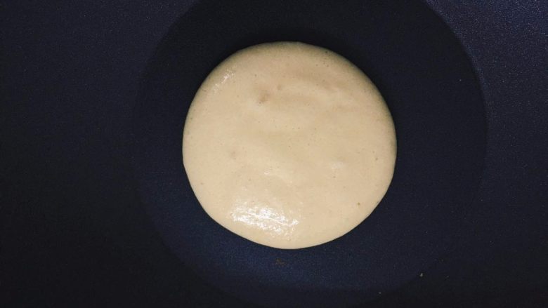 如何轻松制作一个完美的Pancake,用勺子把面糊摊成圆形,注意动作要快点,要不然底面会出来一圈一圈的痕迹,上色就不均匀了。