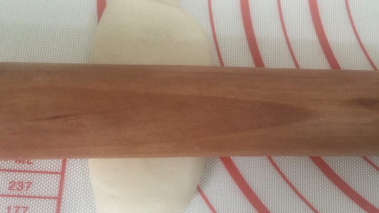 豆沙麻薯蛋黄酥,松弛好的油皮再次擀开,用手按扁,用擀面杖中间轻轻按压下,往下推下在往前推开