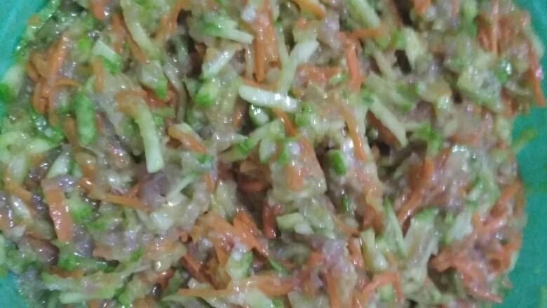 西葫芦胡萝卜牛肉蒸饺,顺着一个方向搅拌,这个时候可以加几滴香油提香,直到馅料充分的搅拌均匀