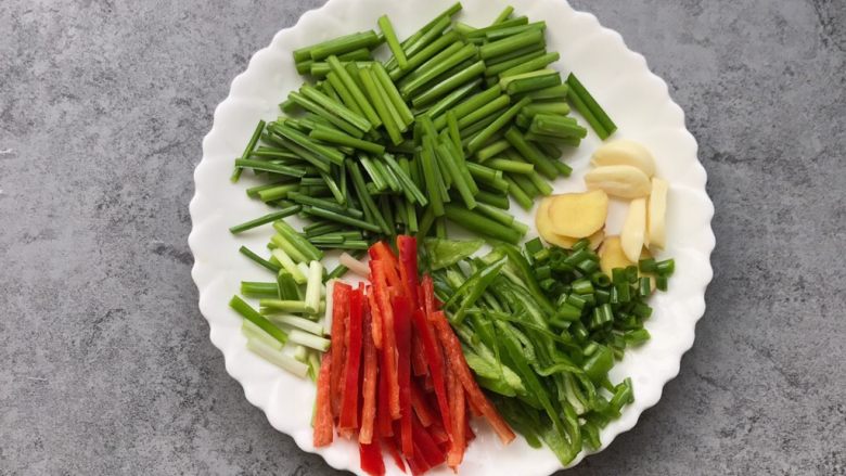 家常小炒肉丝,韭菜苔切小段,青红椒切丝、蒜瓣和姜切片、葱切小段