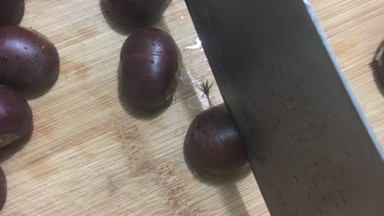 高压锅蒸板栗,放入菜板上,用刀在板栗背上切上一刀,小心手