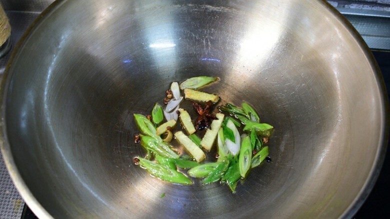 土豆炖豆角,锅中油热,葱、姜、花椒、八角爆香