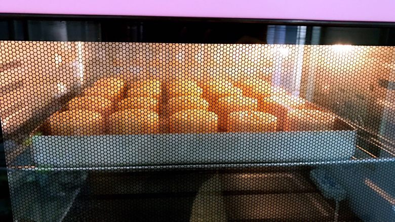 广式低糖莲蓉蛋黄月饼,放入预热好的烤箱里200度中层烤5分钟定型后取出月饼刷蛋黄水,这时烤箱转180度
