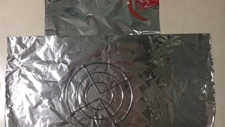 坤博砂锅烤红薯,取两层锡纸交叉摆放后,按烤架的大小包成桶形。