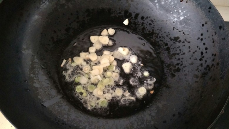 油菜炒香菇,锅里放油加热,放入蒜片和葱花炒香