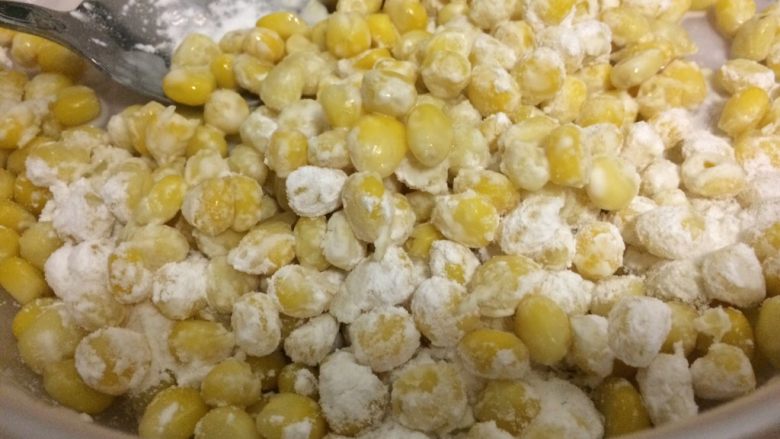 金沙玉米,把玉米淀粉倒入玉米粒中,使玉米粒均匀沾上粉。