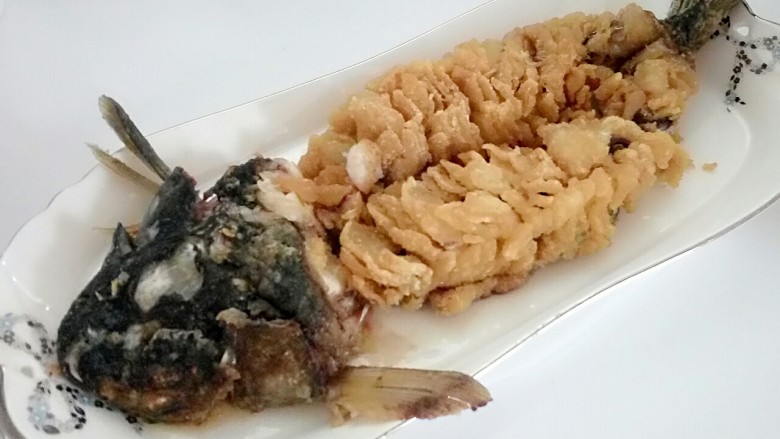 松鼠桂鱼,鱼摆放盘子里,用干净布垫在鱼头压扁。