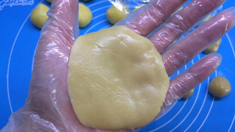 自制奶黄馅广式小月饼,取一个面团,用右手手掌压扁