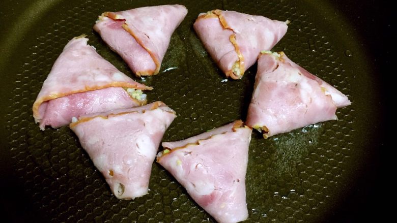 培根包饭—小小炒饭的另一种高大上吃法,平底不粘锅倒入适量植物油,放入培根包饭,盖上锅盖小火煎。