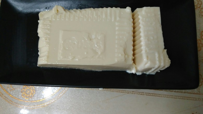 咸蛋肉松牛油果夹豆腐,按住切掉的部分,把豆腐扣入盘子里,然后把切掉的部分根据刚才的宽度改刀,让他们宽度保持一致。