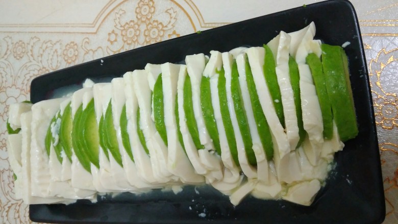 咸蛋肉松牛油果夹豆腐,把牛油果片插进豆腐夹缝中,这部很容易插破,要小心。插好后的豆腐微波炉加热一分钟,把析出来的汤汁倒掉,注意倒汤汁时要小心护着豆腐,或者用厨房纸巾,在盘子边缘吸一吸汤汁也可以。