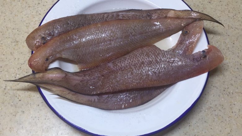 水煮龙舌鱼,将龙舌鱼刮去鱼鳞,剪去肚子洗净,加入盐腌制5分钟。