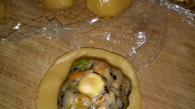 五仁月饼,月饼皮按压成饼,取一块馅料,慢慢推月饼皮,包裹好馅,建议新手用1:1的比例。放入月饼模子,压模,放入烤盘。
