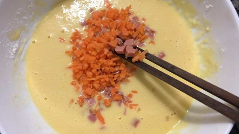火腿胡萝卜鸡蛋饼,然后把火腿肠粒和胡萝卜粒倒入打好的蛋粉里面,进行顺时针的搅拌
